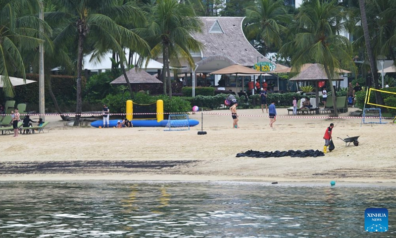 A worker removes a bag filled with oil sludge on Siloso beach of Sentosa island in Singapore, June 15, 2024. The Netherlands-flagged dredger Vox Maxima collided with Singapore-flagged bunker vessel Marine Honor at the Pasir Panjang Terminal on Friday, leading to oil leakage, said the Maritime and Port Authority of Singapore (MPA). (Xinhua/Then Chih Wey)