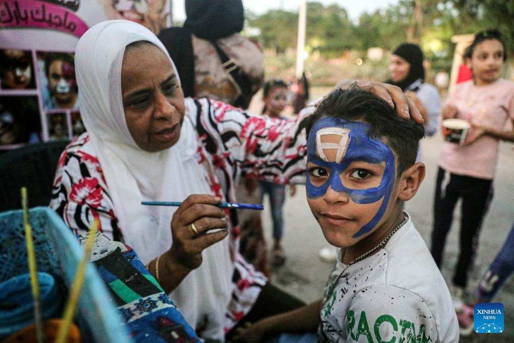 A woman works on face painting for a boy at an amusement park during the Eid al-Adha holiday in Cairo, Egypt, on June 17, 2024.(Photo: Xinhua)