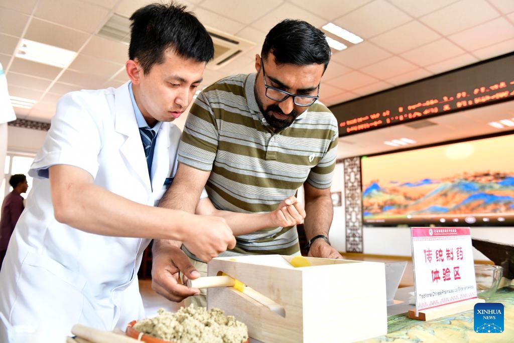 An international student from Qingdao University (R) learns the art of crafting moxa sticks used in moxibustion at a traditional Chinese medicine (TCM) hospital in Qingdao, east China's Shandong Province, June 18, 2024. Some international students from Qingdao University visited a local TCM hospital on Tuesday to experience the charm of TCM culture. Collaborated with several universities in the city, the hospital built a TCM experience base that has hosted more than 600 international students. (Photo: Xinhua)