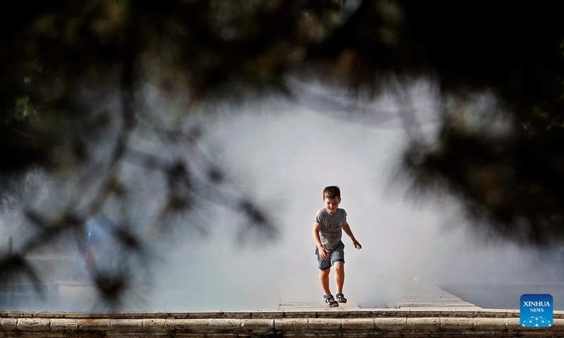 A child passes through the spray of a public fountain to cool off amid a heatwave in Bucharest, Romania, June 22, 2024. (Photo: Xinhua)