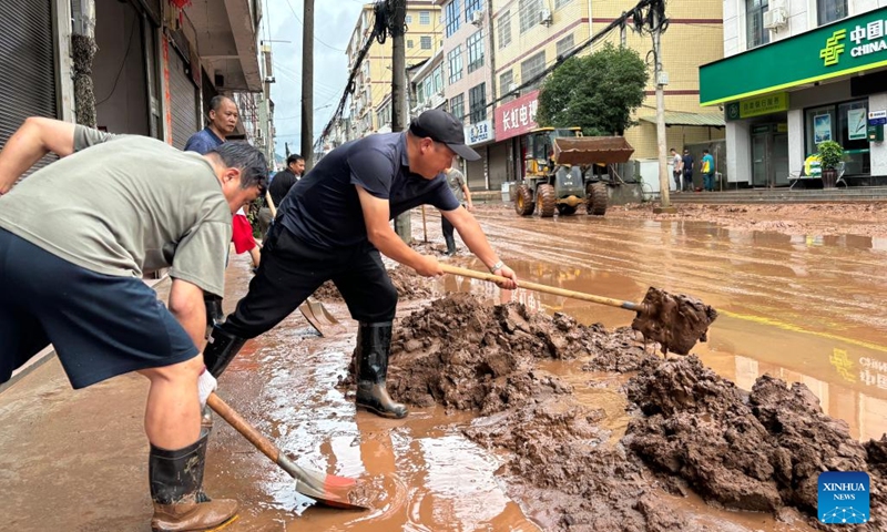 This photo taken by a mobile phone on June 23, 2024 shows people cleaning the mud on a road in Wuqiangxi Township of Yuanling County in central China's Hunan Province. Heavy rainfall hit Wuqiangxi Township on Saturday, triggering flood that impacted local residential area. Local authorities have carried out emergency response to minimize the impact of the extreme weather conditions. (Photo: Xinhua)