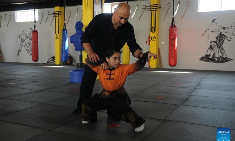 Burhan (back) corrects a student's Wushu movement at a Wushu club in Sulaymaniyah, Iraq, June 12, 2024.(Photo: Xinhua)