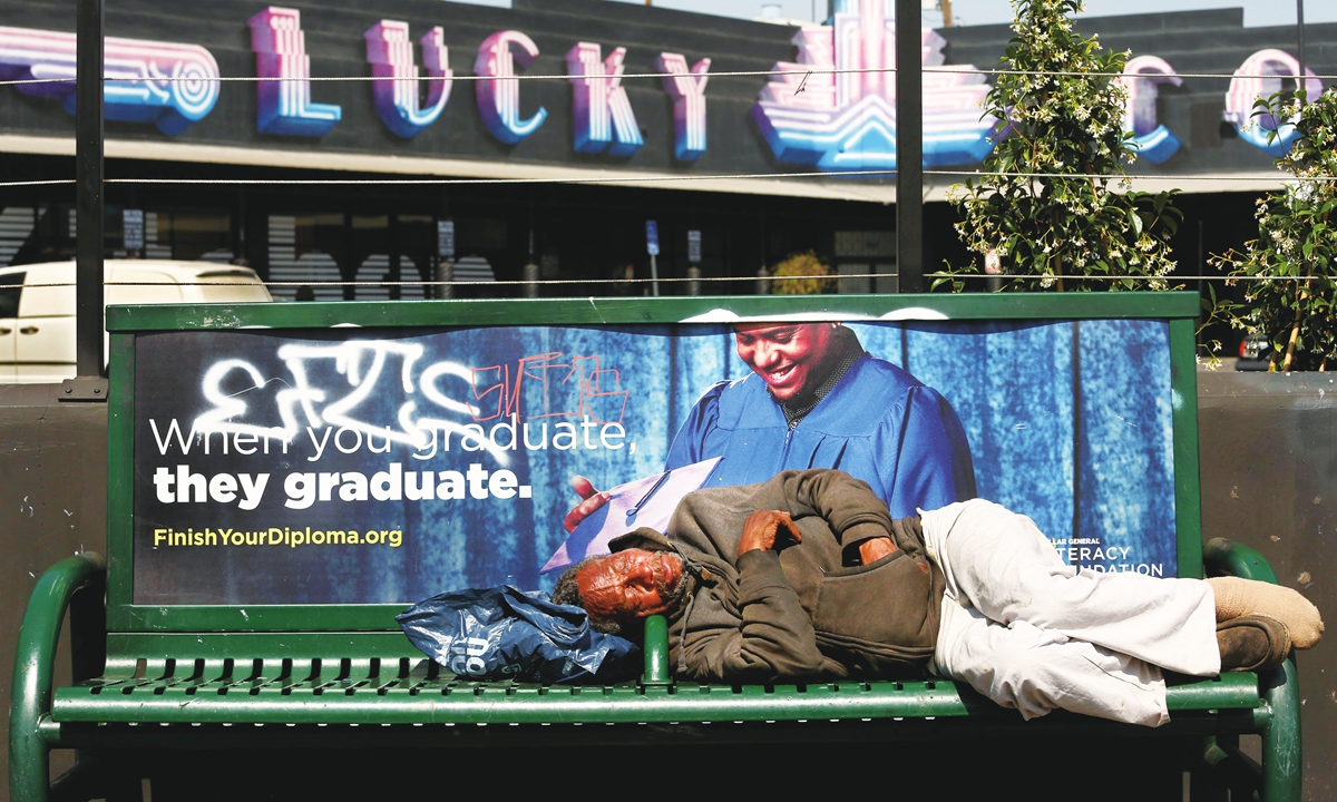A homeless man sleeps on a bus bench in downtown Los Angeles on June 14, 2024
