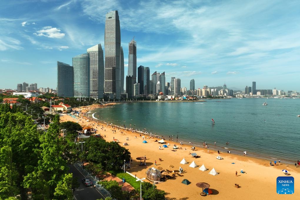 A drone photo taken on June 24, 2024 shows tourists enjoying themselves at a beach in Qingdao, east China's Shandong Province. Tourism in Qingdao is heating up as domestic and foreign tourists come here to enjoy the coastal scenery and cool off in hot summer days.(Photo: Xinhua)