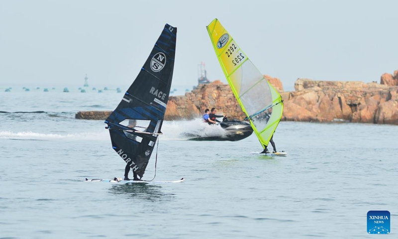 Tourists take motorboats and go windsurfing in Qingdao, east China's Shandong Province, June 24, 2024. Tourism in Qingdao is heating up as domestic and foreign tourists come here to enjoy the coastal scenery and cool off in hot summer days.(Photo: Xinhua)