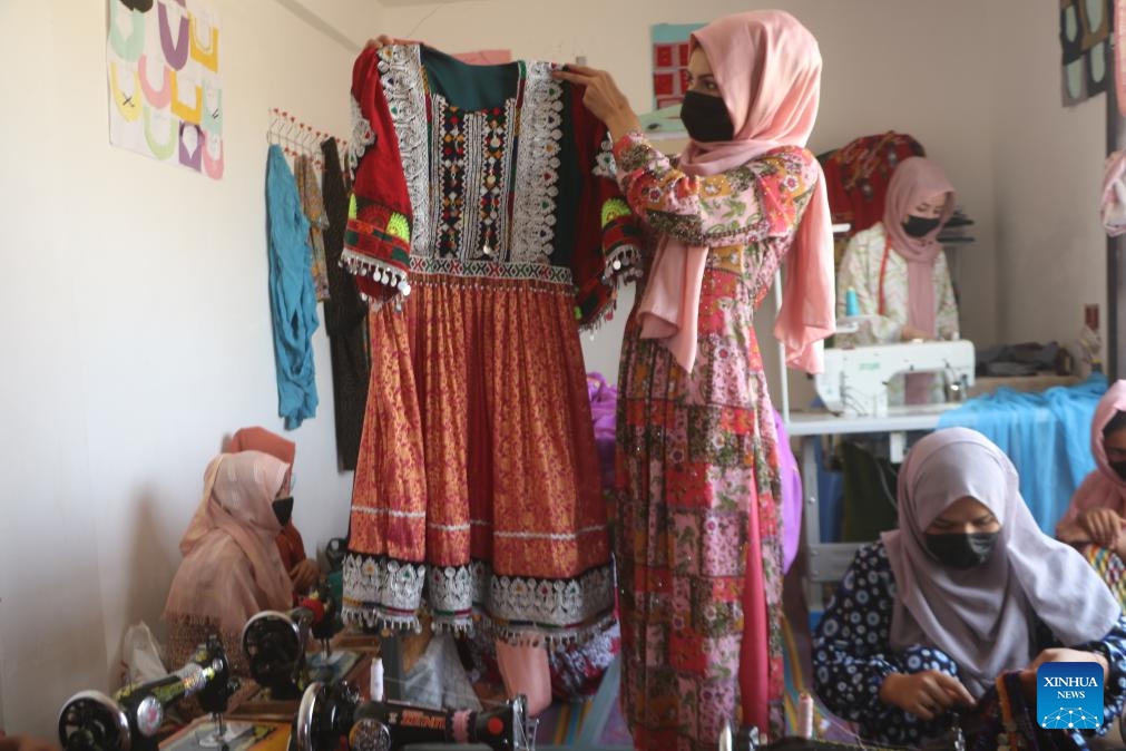 A woman shows a traditional dress at a tailor workshop run by a woman entrepreneur in Jawzjan province, Afghanistan, July 14, 2024. (Photo by Ahmad Zubair/Xinhua)