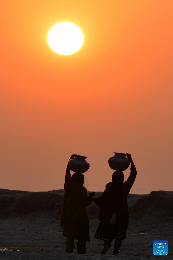 This photo taken on July 17, 2024 shows the silhouette of a woman walking at sunset carrying a water pot on her head in southern Pakistan's Hyderabad. (Photo: Xinhua)