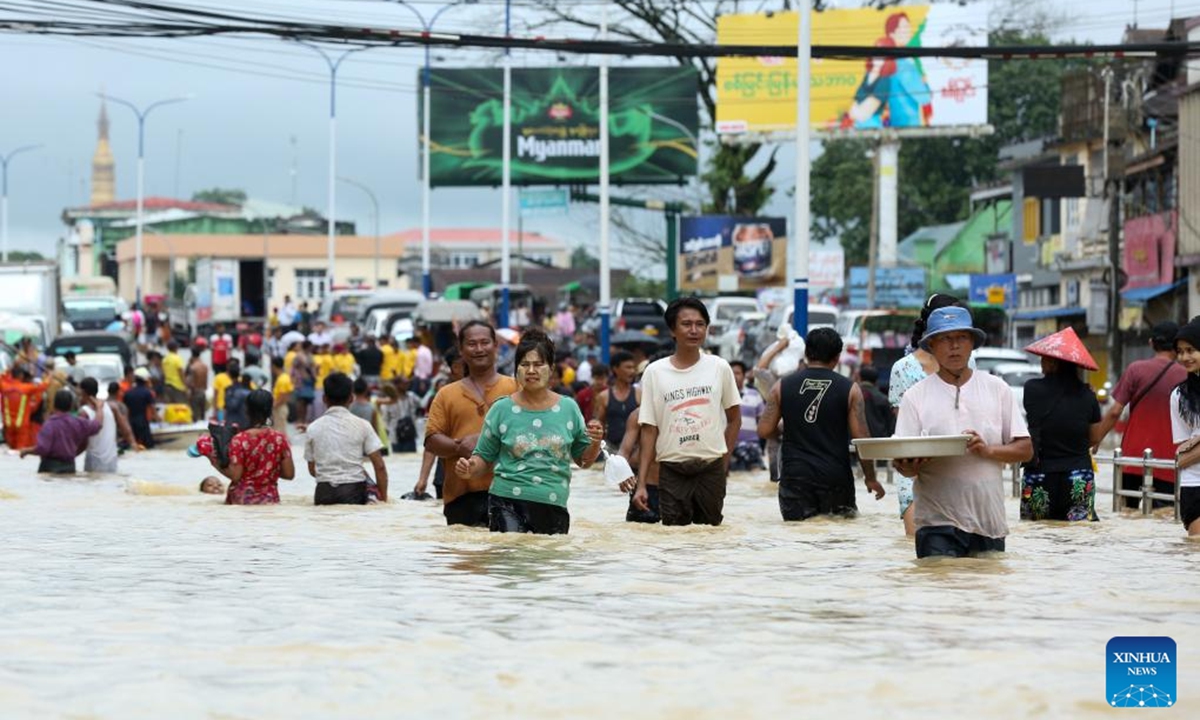 People wade through a flooded area in Bago Region of southern Myanmar, July 29, 2024. (Photo: Xinhua)