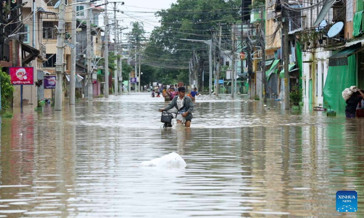 People wade through a flooded area in Bago Region of southern Myanmar, July 29, 2024. (Photo: Xinhua)