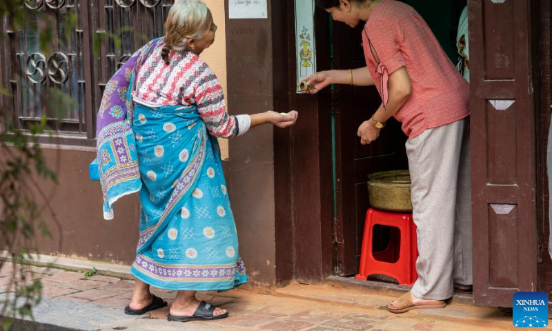 A Buddhist distributes an offering during the Pancha Dan festival in Lalitpur, Nepal, on Aug. 12, 2024. Pancha Dan, the festival of five summer gifts, is observed by the Buddhists by giving away five elements including wheat grains, rice grains, salt, money and fruit. (Photo: Xinhua)