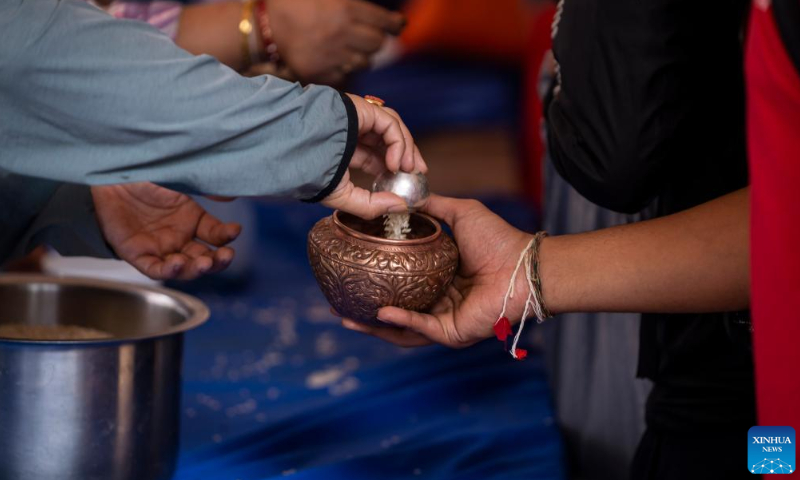 An offering is distributed during the Pancha Dan festival in Lalitpur, Nepal, on Aug. 12, 2024. Pancha Dan, the festival of five summer gifts, is observed by the Buddhists by giving away five elements including wheat grains, rice grains, salt, money and fruit. (Photo: Xinhua)