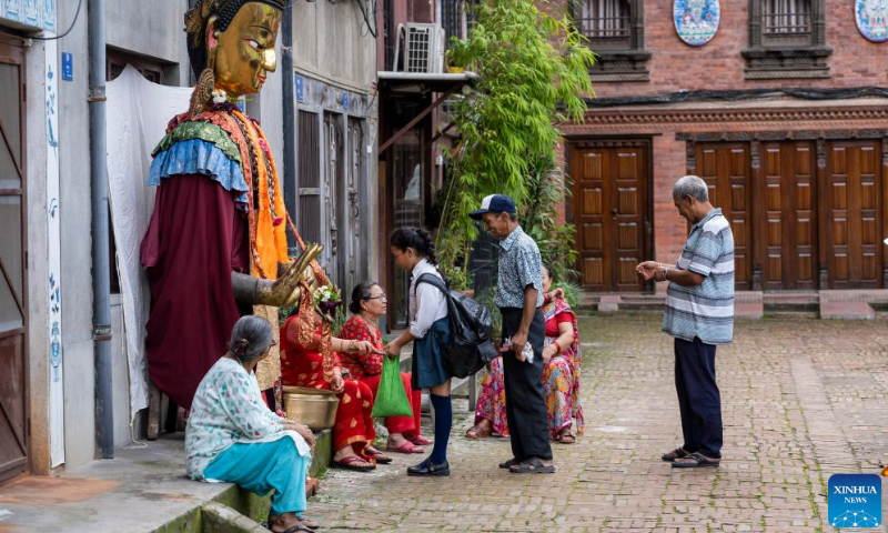 A Buddhist distributes an offering during the Pancha Dan festival in Lalitpur, Nepal, on Aug. 12, 2024. Pancha Dan, the festival of five summer gifts, is observed by the Buddhists by giving away five elements including wheat grains, rice grains, salt, money and fruit. (Photo: Xinhua)