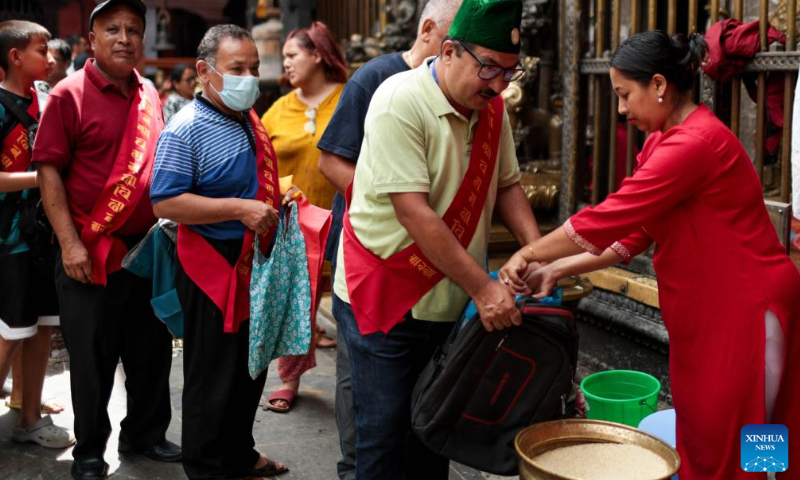 A Buddhist distributes an offering during the Pancha Dan festival in Lalitpur, Nepal, on Aug. 12, 2024. Pancha Dan, the festival of five summer gifts, is observed by the Buddhists by giving away five elements including wheat grains, rice grains, salt, money and fruit. (Photo: Xinhua)