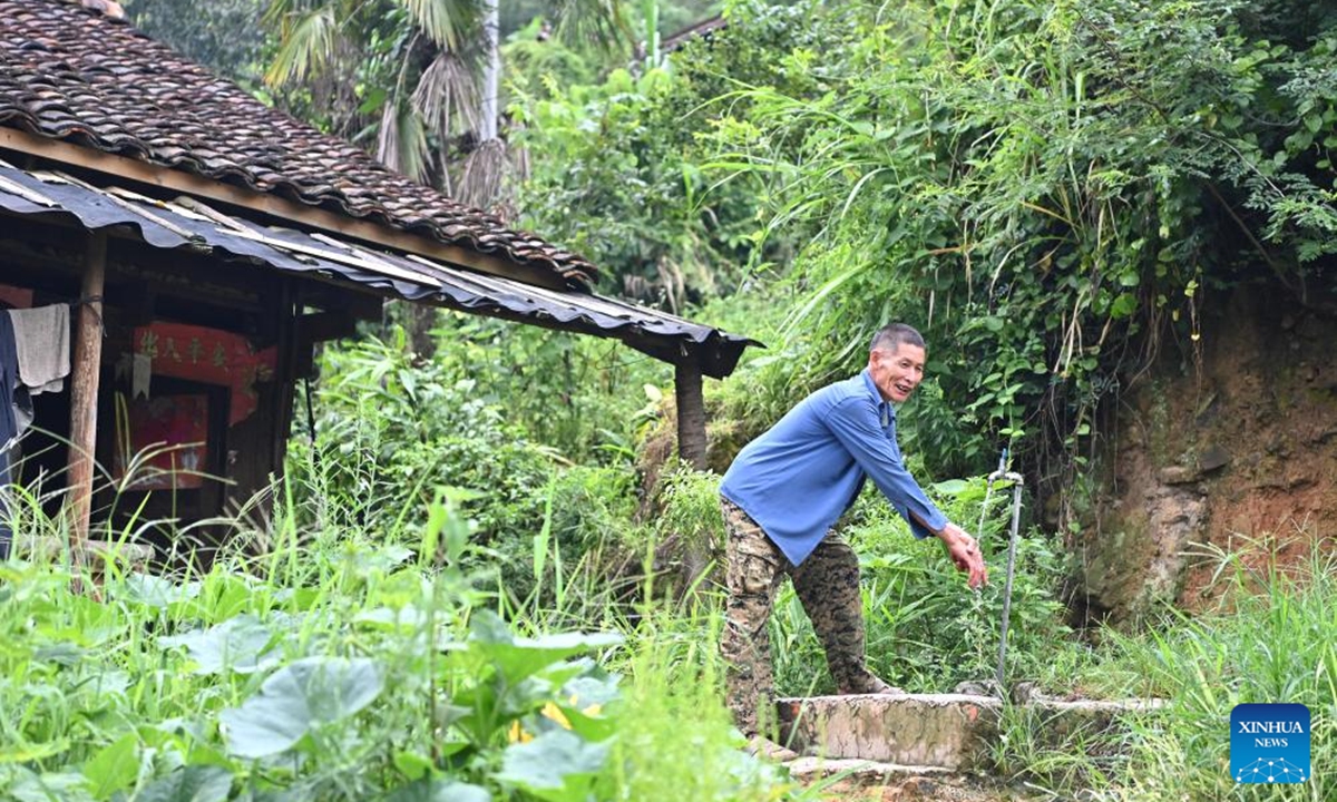 A villager washes hands in front of his wooden Ganlan building in Pingliu Village of Longlin County in south China's Guangxi Zhuang Autonomous Region, July 31, 2024. Pingliu Village, spanning a history of over 200 years, is a Zhuang ethnic-minority hamlet that borders neighboring provinces of Yunnan and Guizhou. Among the well preserved traditions and costumes of the local Zhuang ethnic minority group, the local housing facility, Ganlan building, a stilt wood-structured residential architecture, is most distinctive. (Photo: Xinhua)
