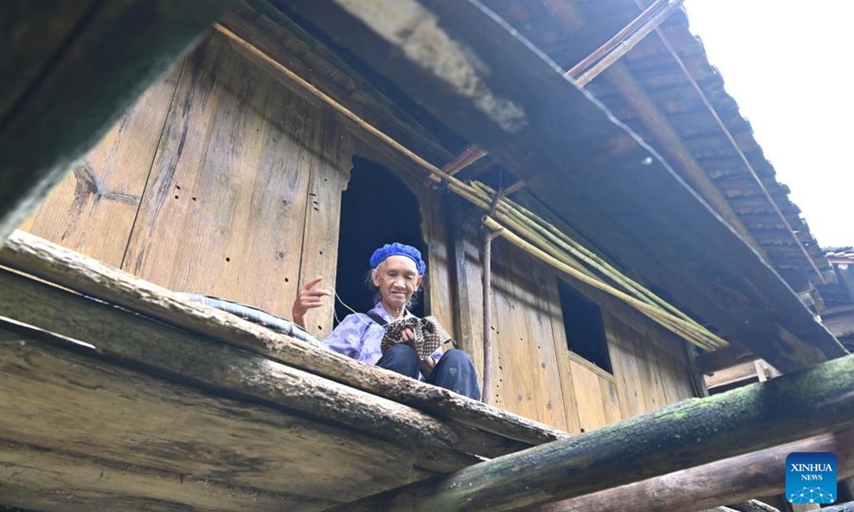 A villager does needlework inside her wooden Ganlan building in Pingliu Village of Longlin County in south China's Guangxi Zhuang Autonomous Region, July 31, 2024. Pingliu Village, spanning a history of over 200 years, is a Zhuang ethnic-minority hamlet that borders neighboring provinces of Yunnan and Guizhou. Among the well preserved traditions and costumes of the local Zhuang ethnic minority group, the local housing facility, Ganlan building, a stilt wood-structured residential architecture, is most distinctive. (Photo: Xinhua)