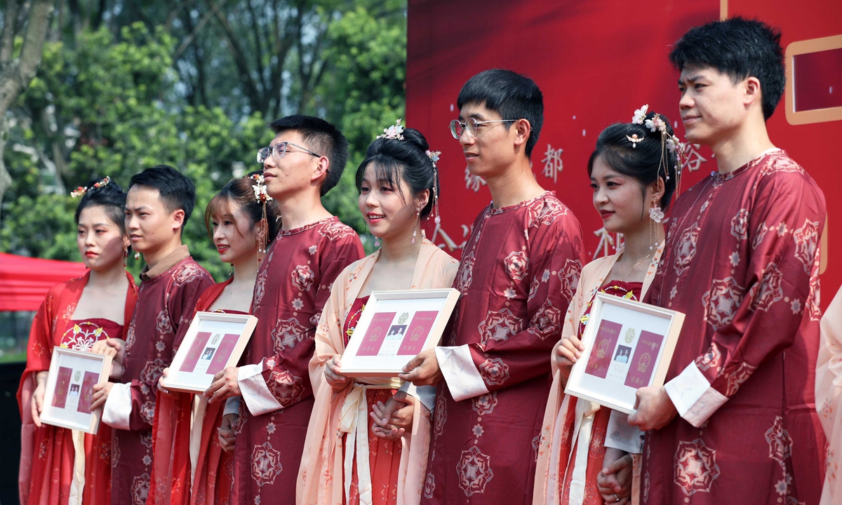 Newlyweds display their marriage certificates on the day of the Qixi Festival in Chengdu, Sichuan Province. Photo: VCG