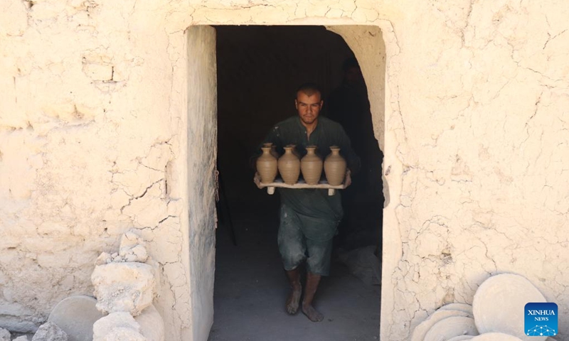 A potter carries pottery pots in Dawlat Abad District, north Afghanistan's Balkh province, Aug. 7, 2024. (Photo: Xinhua)