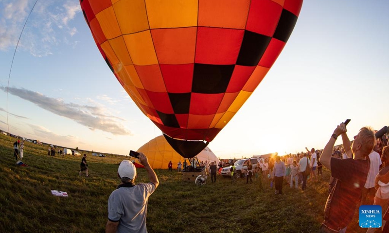 People take photos of a hot-air balloon during the Sky of Russia hot-air balloon festival in Ryazan region, Russia, on Aug. 9, 2024. The 22nd ballooning festival Sky of Russia is held here from Aug. 4 to 12, and more than 30 teams are featured in the festival. Photo: Xinhua