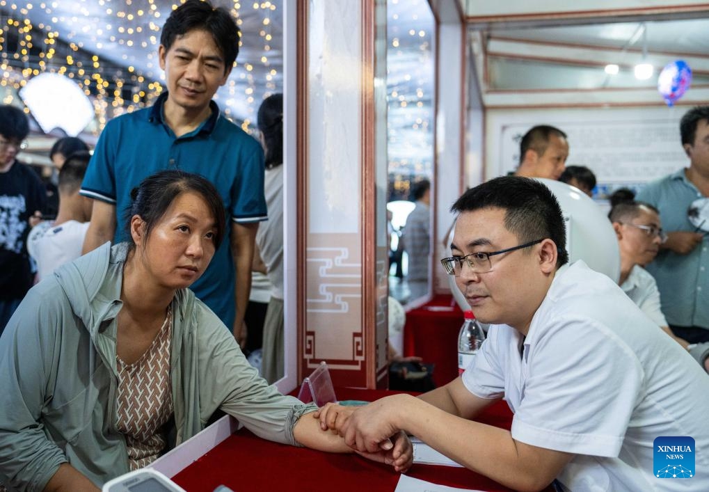 A medical worker (R) takes a citizen's pulse at a night traditional Chinese medicine clinic in Changning City, central China's Hunan Province, Aug. 13, 2024. Local health bureau of Changning City has launched a night clinic, where traditional Chinese medical therapies and treatment services, such as acupuncture, moxibustion, remedial massage, etc., are available to residents for free. The clinic will last until Aug. 18.  (Photo: Xinhua)