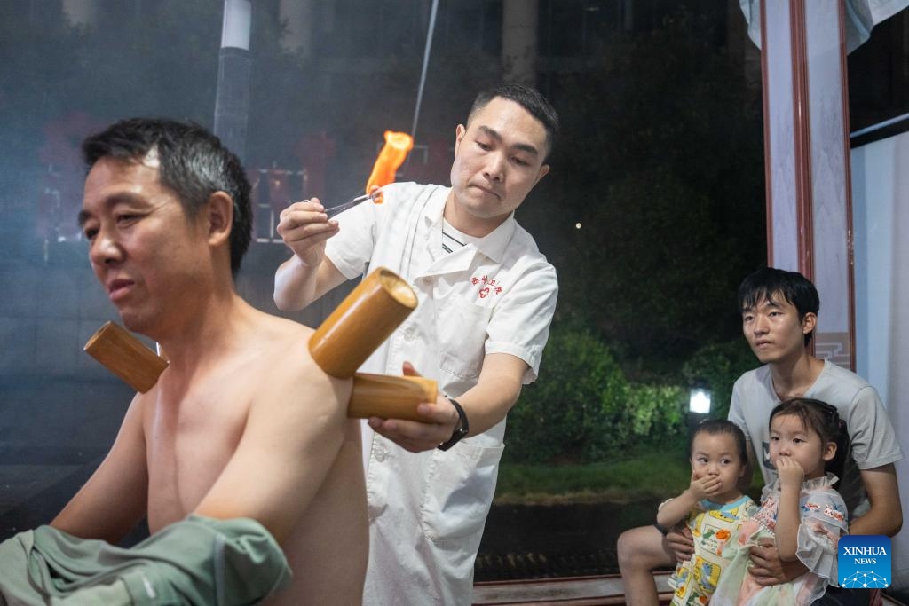 A medical worker (2nd L) provides cupping therapy to a citizen at a night traditional Chinese medicine clinic in Changning City, central China's Hunan Province, Aug. 13, 2024. Local health bureau of Changning City has launched a night clinic, where traditional Chinese medical therapies and treatment services, such as acupuncture, moxibustion, remedial massage, etc., are available to residents for free. The clinic will last until Aug. 18.  (Photo: Xinhua)
