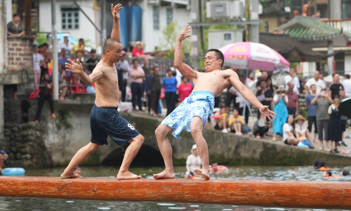 Two villagers compete on a beam above the water in a village in Liuzhou, South China's Guangxi Zhuang Autonomous Region on August 19, 2024. During the fun event held by the village, villagers enjoyed the joy of sports in games such as water tug-of-war, water ring and duck grabbing in the water. Photo: VCG