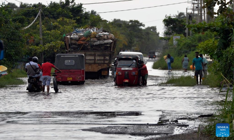 People and vehicles wade through floodwater on a waterlogged road in Wattala, Sri Lanka, on Aug. 18, 2024. Photo: Xinhua