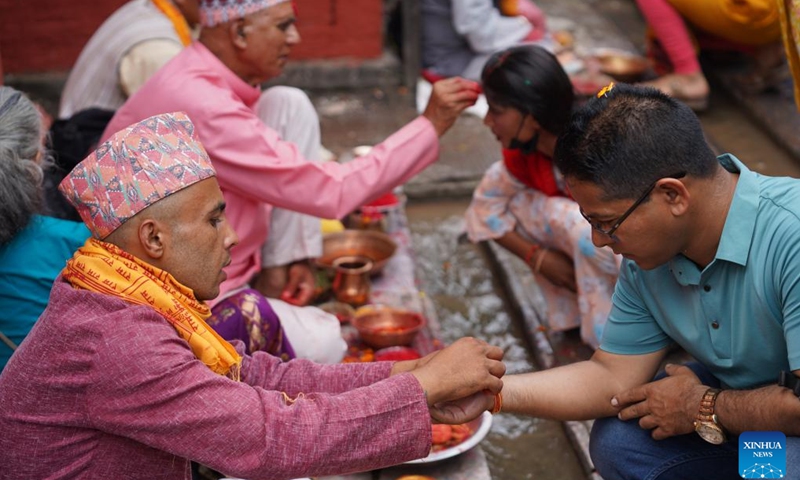 A priest ties a sacred string to a devotee during the Janai Purnima festival in Lalitpur, Nepal, Aug. 19, 2024. (Photo: Xinhua)