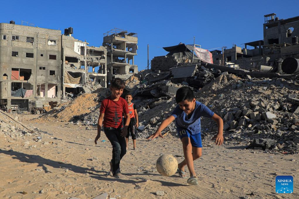 Palestinian children play football beside building rubble in the southern Gaza Strip city of Khan Younis, Aug. 20, 2024. (Photo: Xinhua)