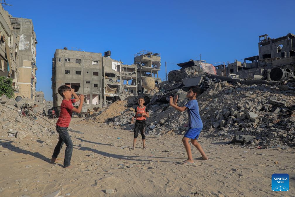 Palestinian children play football beside building rubble in the southern Gaza Strip city of Khan Younis, Aug. 20, 2024. (Photo: Xinhua)