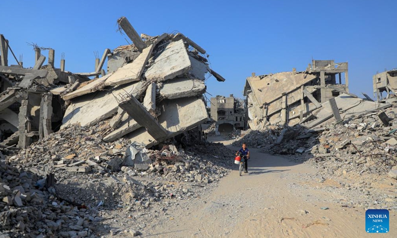 A child rides a bicycle among rubble of damaged buildings in the southern Gaza Strip city of Khan Younis, on Aug. 26, 2024. (Photo: Xinhua)