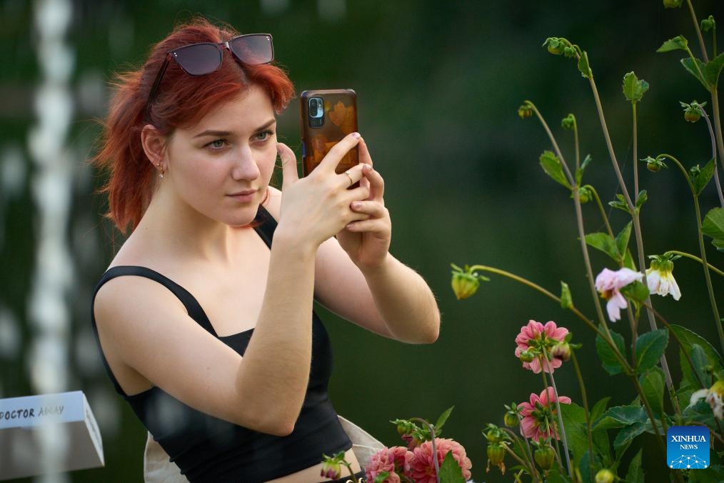 A woman takes photos of flowers at the Royal Lazienki Park in Warsaw, Poland, on Aug. 29, 2024. After a month of repairing some facilities damaged by a thunderstorm in late July, the park has recently reopened to the public. (Photo: Xinhua)
