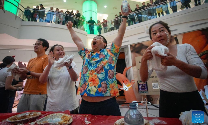 A contestant raises arms to celebrate his winning at the pumpkin pie eating contest at Metrotown Shopping Mall in Burnaby, British Columbia, Canada, Oct. 19, 2024.
The competition required participants to finish as much of a 2-pound pie as possible in 5 minutes without using their hands. (Photo: Xinhua)