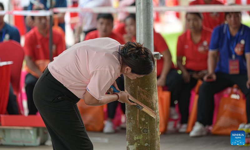 A contestant taps a mock rubber tree during the final round of a rubber tapping contest as part of a national vocational skills competition for agricultural practitioners, in Haikou, south China's Hainan Province, Oct. 21, 2024. A total of 70 contestants attend the final round held here on Monday. (Photo: Xinhua)