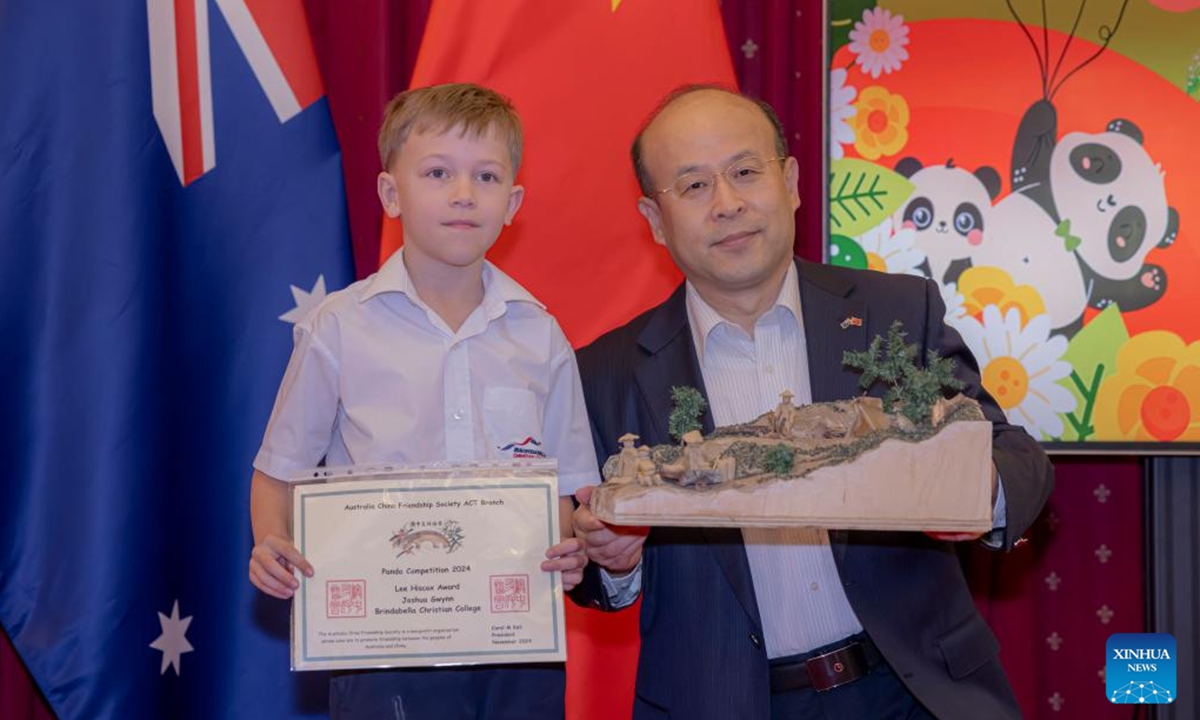 Chinese Ambassador to Australia Xiao Qian poses for photos with a prize winner during the Panda Competition at the Chinese Embassy in Australia, in Canberra, Australia on Nov. 6, 2024. Australian children in Canberra were awarded on Wednesday for their paintings, sculptures, poems, creative collage and constructions surrounding the subject of the Chinese and the Australian gold rushes. (Photo: Xinhua)