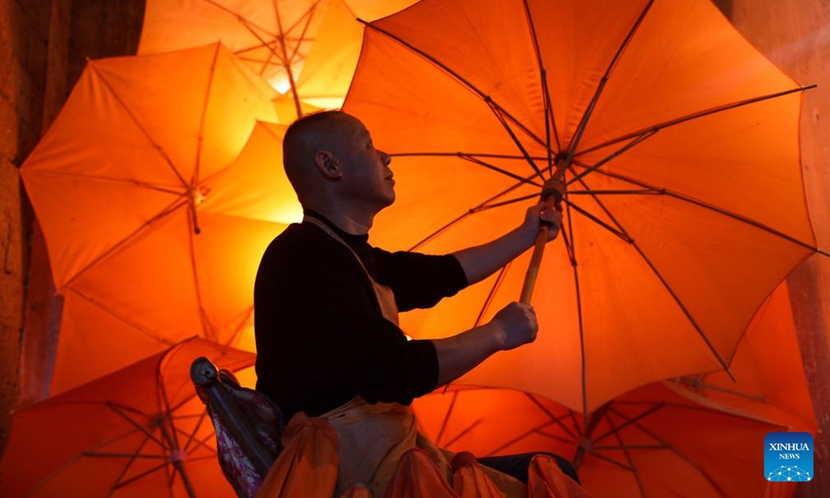 Zheng Guomin, a provincial-level inheritor of intangible cultural heritage, checks an oilcloth umbrella at Guomin Oilcloth Umbrella Plant in Gufeng Village of Jingxian County, east China's Anhui Province, Nov. 13, 2024. The umbrella, made of oiled cloth and bamboo frame, is a traditional Chinese handicraft. (Photo: Xinhua)