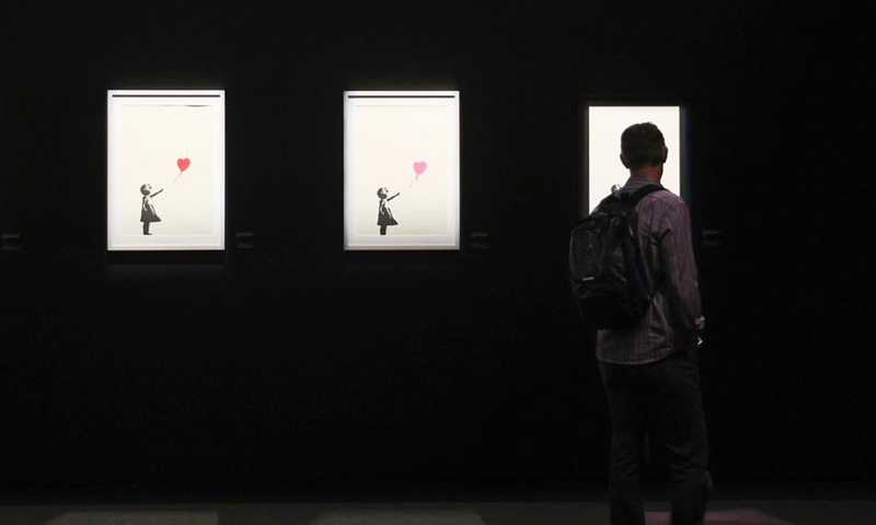 A visitor views an artwork of British street artist Banksy during the exhibition The Art of Banksy in Wellington, New Zealand, on Dec. 3, 2024. Photo: Xinhua