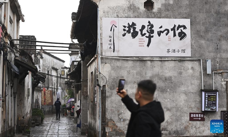 A tourist takes photos of ancient buildings at the Youbu ancient town of Lanxi City, east China's Zhejiang Province, Dec. 5, 2024. Youbu ancient town, with a history of more than 1,300 years, is well known for its morning tea and photography elements and attracts a large number of tourists. (Photo: Xinhua)