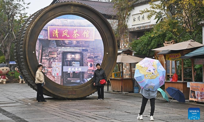 Tourists pose for photos in front of a sculpture in the shape of a camera lens at the Youbu ancient town of Lanxi City, east China's Zhejiang Province, Dec. 5, 2024. Youbu ancient town, with a history of more than 1,300 years, is well known for its morning tea and photography elements and attracts a large number of tourists. (Photo: Xinhua)