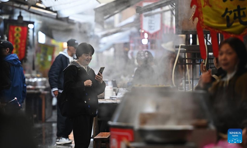 A tourist visits a morning tea street at the Youbu ancient town of Lanxi City, east China's Zhejiang Province, Dec. 5, 2024. Youbu ancient town, with a history of more than 1,300 years, is well known for its morning tea and photography elements and attracts a large number of tourists. (Photo: Xinhua)