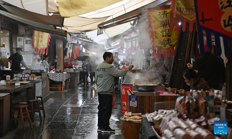 A tourist buys snacks at a morning tea street of the Youbu ancient town, Lanxi City, east China's Zhejiang Province, Dec. 5, 2024. Youbu ancient town, with a history of more than 1,300 years, is well known for its morning tea and photography elements and attracts a large number of tourists. (Photo: Xinhua)