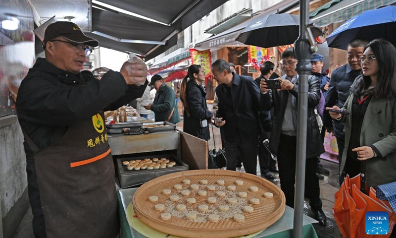 A merchant demonstrates the production process of sesame cake at the Youbu ancient town of Lanxi City, east China's Zhejiang Province, Dec. 5, 2024. Youbu ancient town, with a history of more than 1,300 years, is well known for its morning tea and photography elements and attracts a large number of tourists. Photo: Xinhua