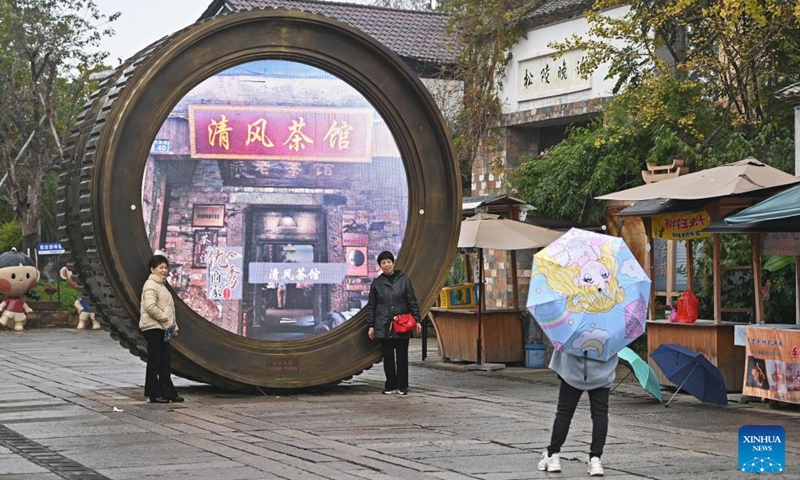 Tourists pose for photos in front of a sculpture in the shape of a camera lens at the Youbu ancient town of Lanxi City, east China's Zhejiang Province, Dec. 5, 2024. Youbu ancient town, with a history of more than 1,300 years, is well known for its morning tea and photography elements and attracts a large number of tourists. Photo: Xinhua