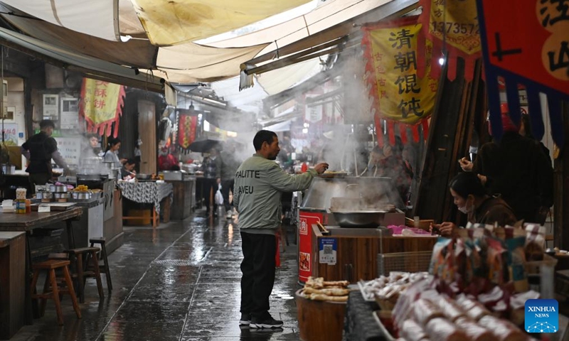 A tourist buys snacks at a morning tea street of the Youbu ancient town, Lanxi City, east China's Zhejiang Province, Dec. 5, 2024. Youbu ancient town, with a history of more than 1,300 years, is well known for its morning tea and photography elements and attracts a large number of tourists. Photo: Xinhua