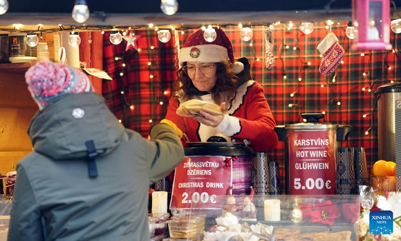 A vendor serves a customer at a Christmas market in Riga, Latvia, Dec. 7, 2024. Photo: Xinhua