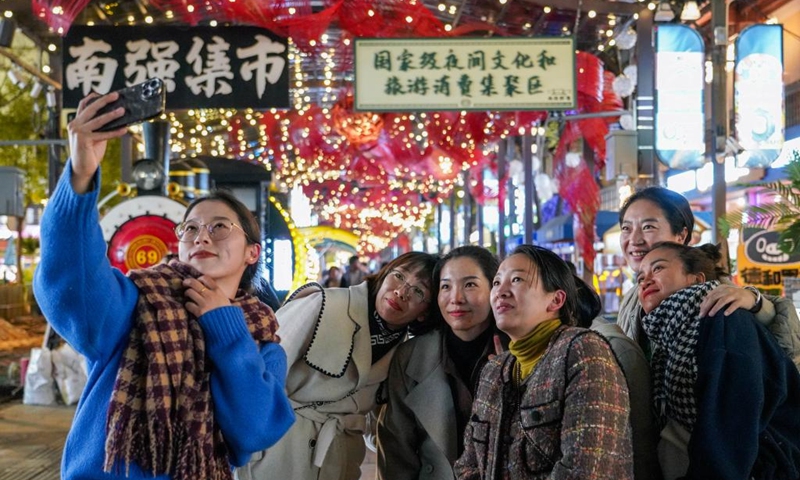 Tourists pose for a photo on a street at night in Kunming City, southwest China's Yunnan Province, Dec. 6, 2024. In recent years, Kunming has stepped up its efforts to enrich citizen's life by developing night fair compounds. Photo: Xinhua