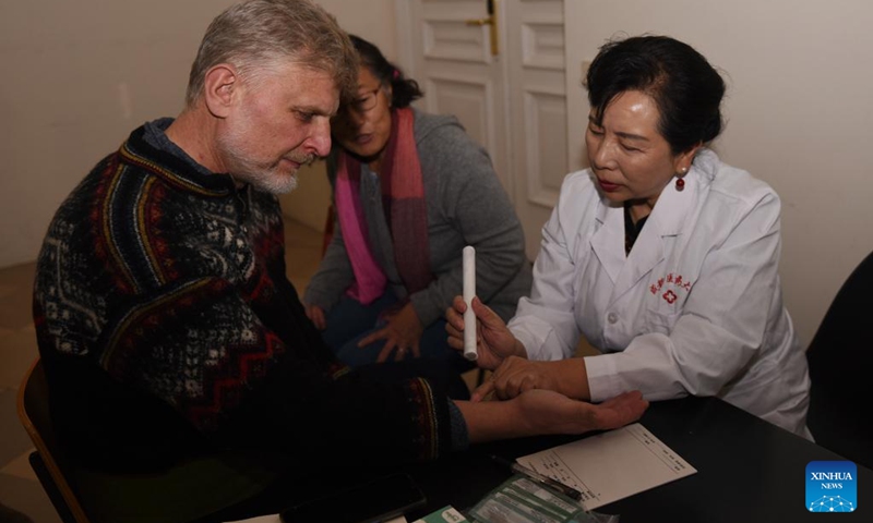 Zhang Hong (R), a professor from Chengdu University of Traditional Chinese Medicine (TCM), introduces moxibustion techniques to a patient during an event in Vienna, Austria, Dec. 7, 2024. An event of TCM free consulting service was held here on Saturday. Photo: Xinhua