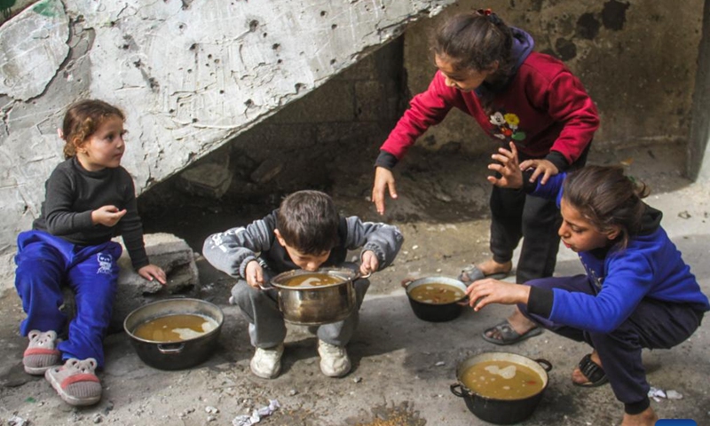 Displaced Palestinian children have food obtained from a local community kitchen amid the siege imposed by the Israeli army and the scarcity of aid in the Al-Shati camp, west of Gaza City, on Dec. 7, 2024. Photo: Xinhua
