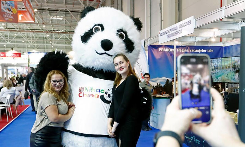 Visitors pose for photos with a giant panda mascot of China's stand at the autumn edition of Romania's Tourism Fair in Bucharest, Romania, Nov. 22, 2024. China's stand attracted visitors at the Romania's Tourism Fair, which is held here from Nov. 21-24, as China has expanded its visa-free policy to nine additional countries including Romania, allowing their citizens to enter for up to 30 days without a visa for business, tourism, and other visits starting Nov. 30, 2024. Photo: Xinhua