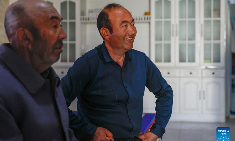Memet Metseyit (R) talks with his family member at home in Pupuk Village of Minfeng County, northwest China's Xinjiang Uygur Autonomous Region, Dec. 4, 2024. (Photo: Xinhua)