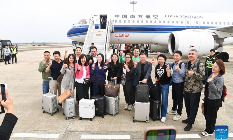 Passengers pose for photos with the C919 aircraft after getting off the plane at Haikou Meilan International Airport in Haikou, south China's Hainan Province, on Dec. 11, 2024.(Photo: Xinhua)